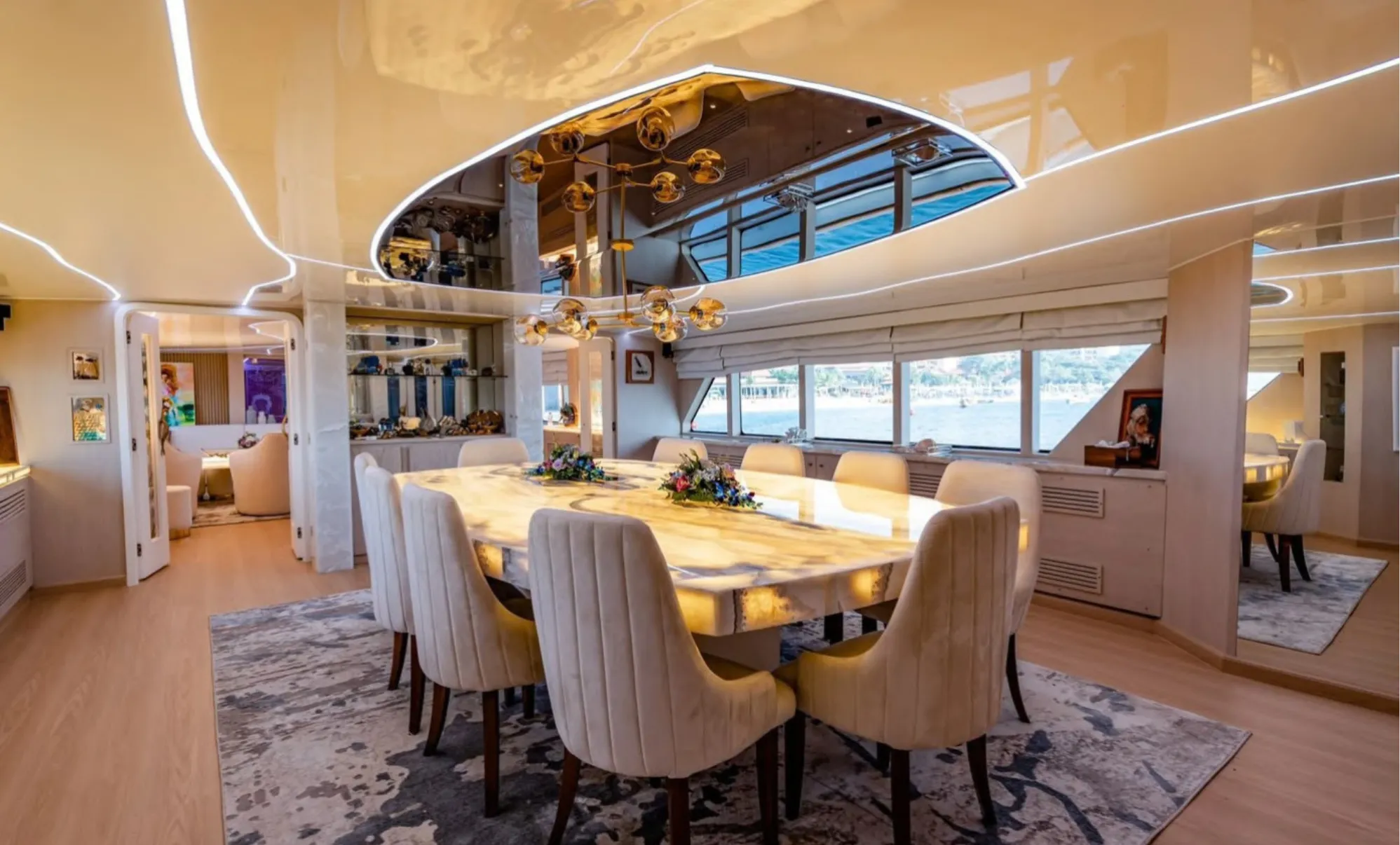 The Seraphine dining saloon with a backlit onyx table and cream chairs under a mirrored ceiling recess